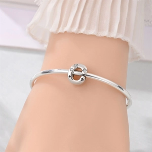 Close-up of silver letter E charm bracelet featuring engraved stars and zircon stones