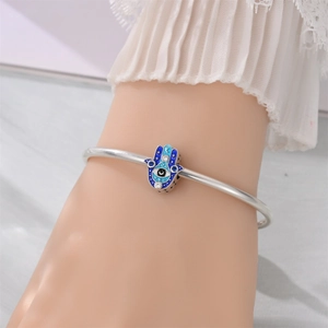 Macro view of silver Hamsa Hand charm with blue enamel evil eye and star details