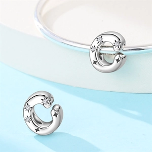 Macro detail of silver C-shaped charm with black stars and white zircon inlays