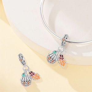 Detailed view of autumn enamel maple leaf and acorn charms with zircon on silver bracelet