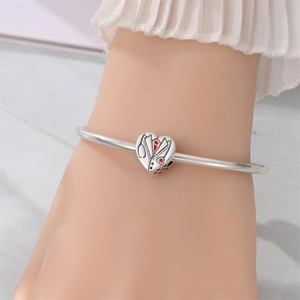 Detail of silver heart charm with medical uniform design on open bangle bracelet