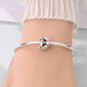 Detailed shot of silver bangle featuring a star-engraved moon charm with zircon stones