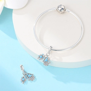 Detail of silver Hamsa Hand and Evil Eye charms with blue beads on a round bangle