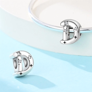Macro shot of silver letter D charm with star engravings and zircon stones for bracelets