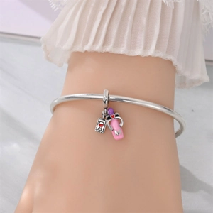 Close-up of silver bangle bracelet with pink charm and red heart detail on a woman's wrist