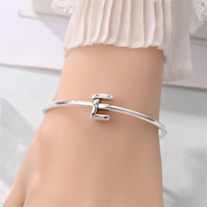 Close-up of a silver letter E charm bracelet with sparkling star-shaped crystal details
