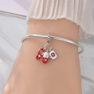 Detail of medical bracelet with red stethoscope, pill, and first aid kit charms