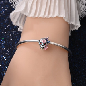 Gedetailleerd beeld van zilveren schedelarmband met kleurrijke bloemmotieven en vlinders