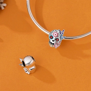 Detailopname van een zilveren schedelbedel met kleurrijk email op een zilveren armband