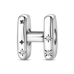 Macro view of silver-plated letter H charm bead with zircon inlay and star patterns