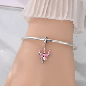 Detail of silver pink enamel candlestick charm with bow on a bracelet worn by model
