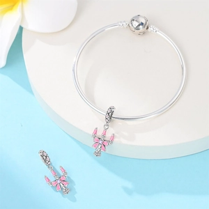 Detail of silver snake chain bracelet featuring pink enamel bow and scepter charm