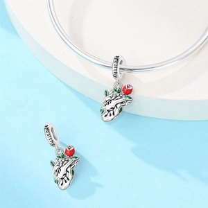 Close-up of silver heart charm with red rose and 'healthy' engraving on the band