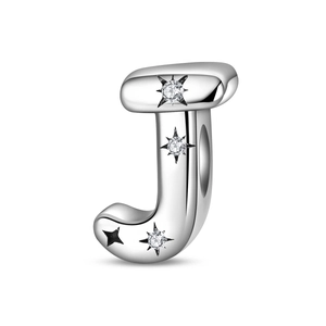 Macro detail of silver letter J charm with inlaid zircons and a black star element