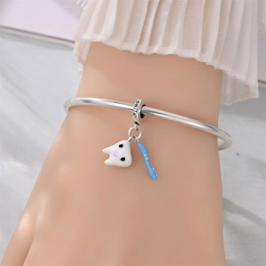 Detail of silver bracelet with tooth charm, toothbrush pendant and Smile engraving