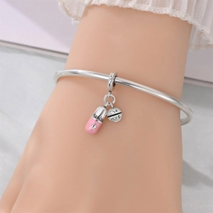 Macro detail of silver charm bracelet featuring pink glitter capsule and DNA HOPE pendant