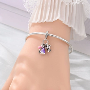 Detail of silver bangle featuring Holland charm, purple windmill, and pink balloon charms