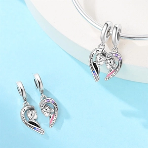 Detail of silver couple's heart charms featuring boy and girl profiles with colored crystals