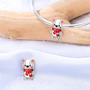 Detalle de abalorio de oso polar plateado con bufanda roja en pulsera invernal