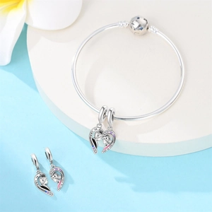 Macro detail of silver snake chain bracelet with heart-shaped couple charm and zircons