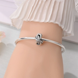 Detail of silver knot charm with sparkling pavé zircons on a round bangle bracelet