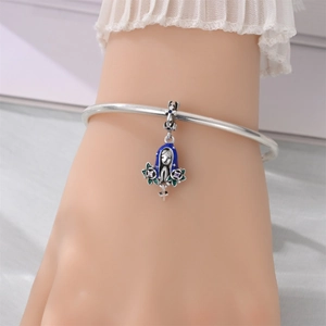 Detail of silver bracelet with colorful enamel religious charm and cross pendant