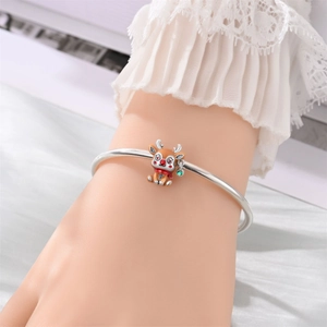 Primer plano de pulsera navideña plateada con dije de reno esmaltado y gema verde joya