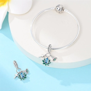 Detailed view of silver charm bracelet with lotus pendant and teardrop blue gemstone