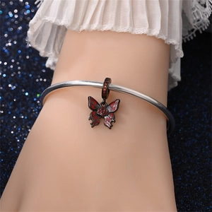 Detail van vlinderbedelarmband met rood en zwart email en roosvormig ontwerp