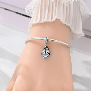 Pulsera de plata con pingüino, cristal azul y esmalte negro en la muñeca de una modelo