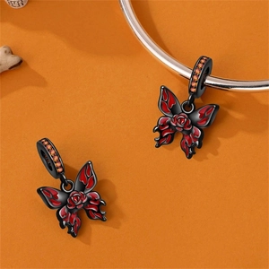 Detail van vlinderbedeltje met rode vuurvleugels en oranje zirkoon aan armband