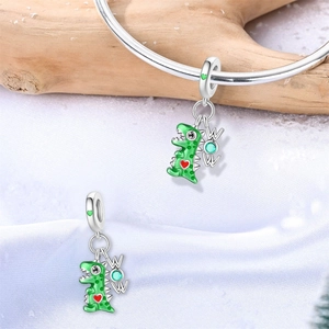 Detail eines grünen Dinosaurier-Anhängers mit rotem Herz und WOW-Anhänger am Armband