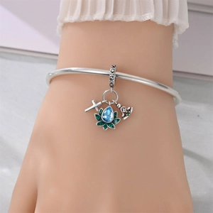 Detailed macro view of silver charm bracelet with blue lotus and crystal cross pendants