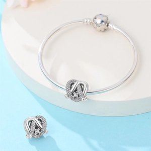 Detailed view of silver snake chain bracelet with sparkling crystal knot charms