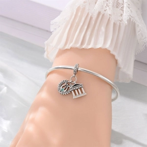 Macro detail of silver charm bracelet featuring Greek Parthenon and green lyre pendants