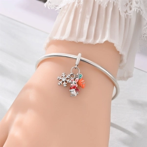 Primer plano de una pulsera de plata con dijes de copo de nieve, conejo esmaltado y zanahoria