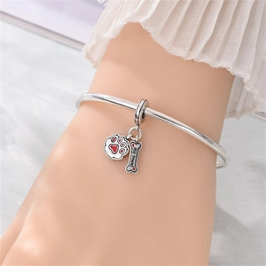 Dettaglio del bracciale in argento S925 con ciondoli a zampa e osso indossato al polso