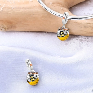 Nahaufnahme von Silber-Bienen-Anhänger mit gelbem Edelstein auf weißem Seidenhintergrund
