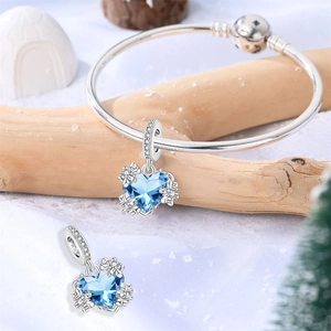 Detailansicht des Schlangenarmbands mit herzförmigen blauen Kristallanhängern im Winterschnee