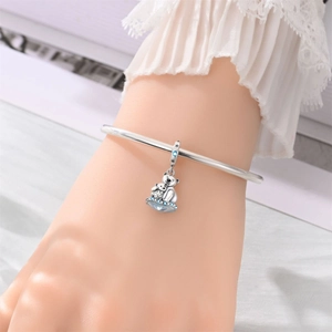Primer plano de un dije de koala plateado con circonitas azules en un brazalete