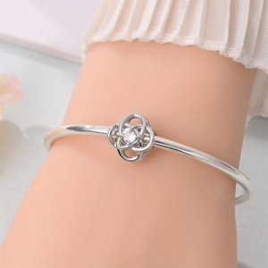 Macro shot of silver knot charm bracelet with a central sparkling zircon stone