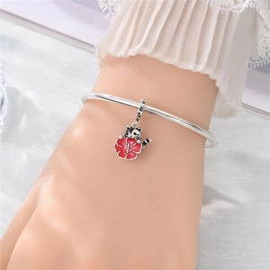 Dettaglio di un bracciale in argento con ciondolo a gatto che tiene un fiore smaltato