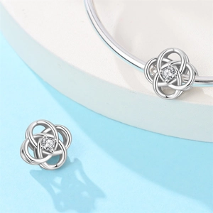 Macro shot of silver-plated knot charm with clear round zircon stone inlay detail