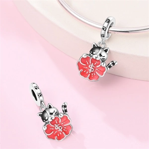 Dettaglio macro di un charm gatto in argento 925 con fiore smaltato rosso e impronte di zampa