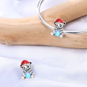 Detalle de dije de oso con gorro de esmalte rojo y estrella azul en una pulsera