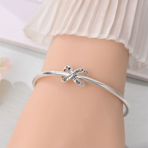 Silver open bangle showing infinity knot detail with Forever engraving and gemstones