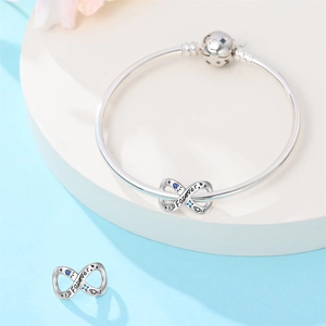 Detailed view of silver infinity charm with Forever engraving and blue stones on bracelet
