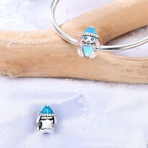 Detalle de dije de conejo plateado con gorro azul y piedra de corazón