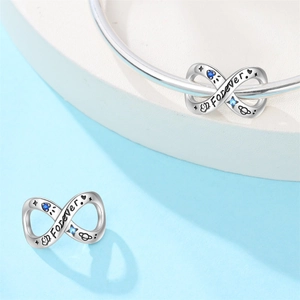 Detailed silver infinity charm with Forever engraving and blue stones on a bracelet