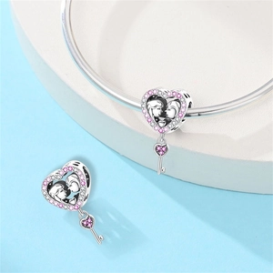 Makroaufnahme vom Herzanhänger aus Silber mit rosa Steinen und kleinem Schlüsselanhänger
